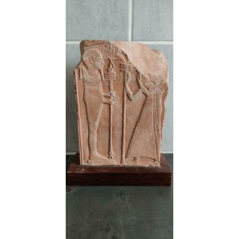 Egyptische steen met hyrogliefen op houten plaat.